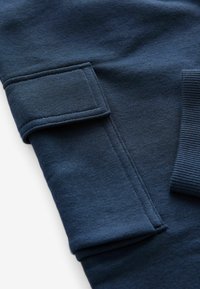 Navyblauwe sweatshirt met een gestructureerd oppervlak, met een paspelzak op de mouw en ribgebreide manchetten voor extra detail en comfort.