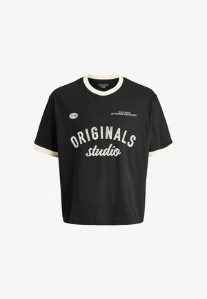 Czarna koszulka z białym napisem "ORIGINALS studio" i jasnym kołnierzykiem; dżinsy z szerokimi nogawkami; jasnobrązowe i kremowe buty. Gładkie tło.