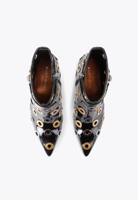 Czarne, lakierowane botki za kostkę z ostrym noskiem, ozdobione złotymi i srebrnymi oczkami, o gładkiej, błyszczącej teksturze.