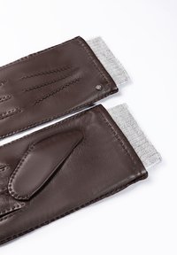 Ein Paar dunkelbraune Lederhandschuhe mit grauen gestrickten Bündchen, flach auf einer weißen Oberfläche ausgelegt, die gestickte Details und Textur zeigen.