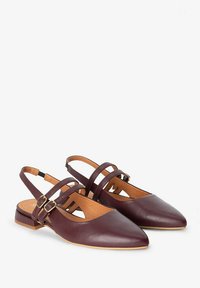 Chaussures à talon bas en cuir bordeaux avec bouts pointus, trois sangles et une semelle en bloc basse. La doublure intérieure est couleur tan. Subtils accents de boucles dorées.
