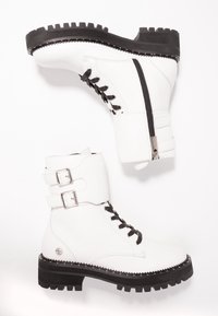 Botas de combate blancas con cordones negros, con un exterior de cuero suave, detalles de hebilla y una suela negra gruesa con borde serrado.