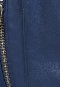 Modrá kůže s hladkým povrchem a výrazným švem, s příslušenstvím stříbrného zipu podél okraje pro funkční detail.