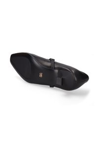 Chaussure en cuir noir avec un bout pointu, une semelle plate et une sangle au niveau de la cheville. Présente une texture antidérapante au talon et un marquage discret.