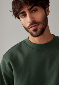 Grüner Baumwoll-Sweatshirt mit Rundhalsausschnitt und gerippten Details. Glatte Textur und etwas lockere Passform, mit Crew-Neck-Design.