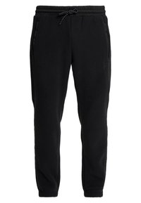 Černé fleecové tepláky s elastickým pasem, šňůrkou, bočními kapsami a zúženými nohavicemi. Obsahují nenápadný detail loga na boku.