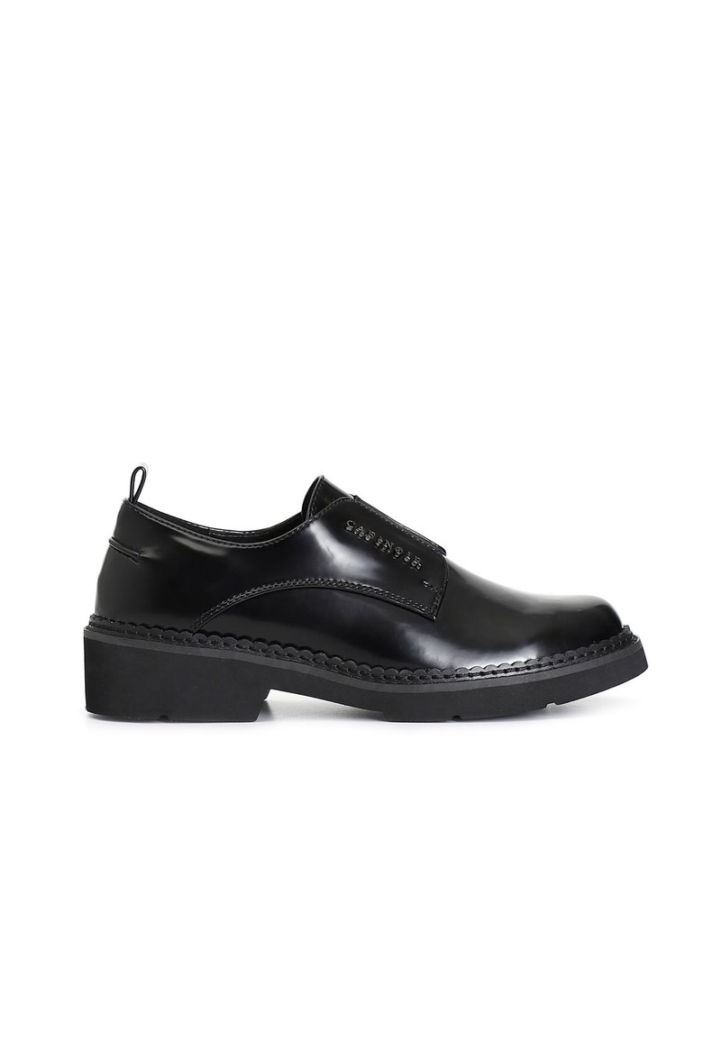 Zapato negro de cuero, tipo mocasín, con punta redondeada, detalle de costura texturizada a lo largo de la suela y un tacón bajo en bloque.