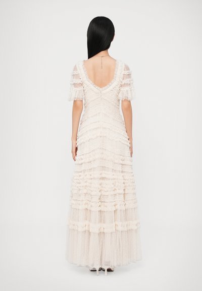 Μακρύ, ωχρό κρεμ φόρεμα από στρωμένα, βολβοειδή τούλια με V-πλάτη και κοντά, φουσκωτά μανίκια. Διαθέτει υφασμάτινο, ριγωτό σχέδιο.