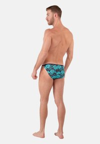 Herren-Schwimmbriefe in Schwarz mit einem blauen Blumenmuster. Mit einem tiefen Schnitt und glattem, elastischem Stoff für mehr Komfort. Geeignet für Wasseraktivitäten.