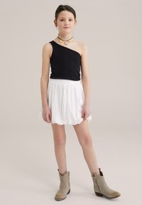 Black one-shoulder top, white flowy skirt with elastic waist, and beige ankle boots. Accessorized with a colorful floral necklace.