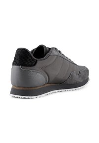 Sneakers grigi con una combinazione di materiali in pelle e suede, un accentuato tacco nero testurizzato e una suola in gomma bianca con scanalature.