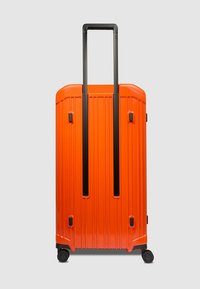 Hartschalenkoffer in leuchtendem Orange, mit vertikalen Rillen, einem ausziehbaren schwarzen Griff und vier Rollen.