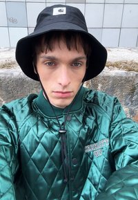 Green quilted jacket with a diamond pattern and black accents, paired with a black bucket hat featuring a logo patch.