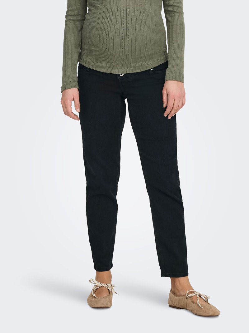 Blugi negri din denim cu croială strâmtă, având un sistem de închidere cu nasturi, și un top cu mâneci lungi, texturat, cu dungi, de culoare verde măsliniu. Balerini maro deschis cu panglică.