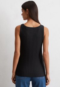 Czarny prążkowany top na ramiączkach z okrągłym dekoltem, o dopasowanym kroju i teksturowanej tkaninie, w połączeniu z niebieskimi dżinsami.