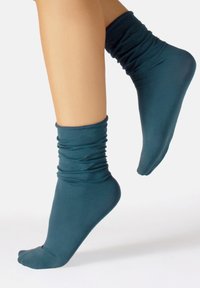 Calze alla caviglia color teal realizzate in materiale liscio ed elasticizzato, con un design arricciato al bordo e una sezione della punta liscia.