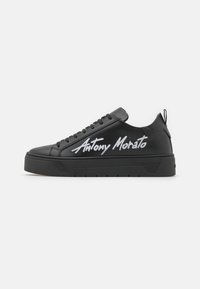 Čierne kožené tenisky s hrubou čiernou gumovou podrážkou. Po boku sa nachádza logo "Antony Morato" v bielej farbe. Jednoduchý dizajn na šnurovanie, bez ozdôb.