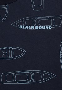 Jūrų tematikos tamsiai mėlynas marškinėliai su šviesiai mėlynomis laivų kontūrais ir užrašu "BEACH BOUND" ryškiu šriftu, sukuriančiu jūrinį raštą audinyje.