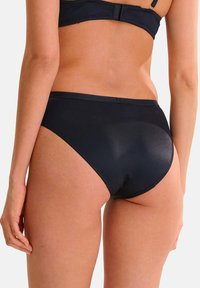 Bas de bikini noir avec une finition satinée lisse, design échancré classique, et des détails de couture minimalisés, offrant une couverture intégrale.