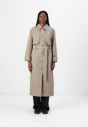 Beige Trenchcoat mit Kragen, seitlichen Taschen und großen Knöpfen. Verfügt über einen taillierten Gürtel und lange Ärmel, der Stoff erscheint glatt.