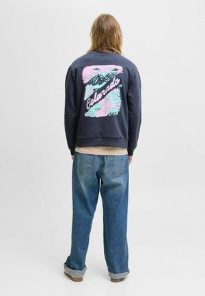 Dark navy sweatshirt with colorful mountain graphic and "Colorado" text on back, paired with loose-fitting blue jeans, and rolled cuffs.