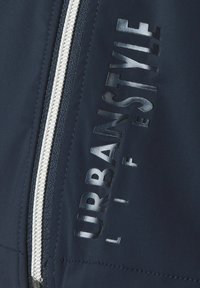 Marinejackenstoff mit glatter Textur, ausgestattet mit einem silbernen Reißverschluss und dem eingeprägten Text "URBANSTYLE LIFE" in glänzender Ausführung an der Seite.