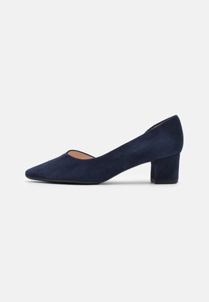Escarpin en daim bleu marine avec un bout pointu et un talon bloc moyen. Texture lisse et design minimaliste, avec un bout ouvert bas.