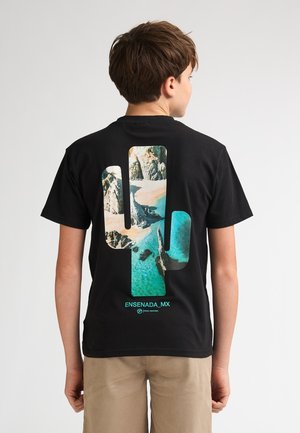 Zwart katoenen T-shirt met een grote cactusafbeelding gevuld met een strandtafereel, bedrukt in kleuren blauw, beige en groen. "ENSENADA_MX" staat eronder gedrukt.