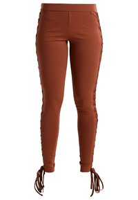 Leggings marrones hechos de un material suave y elástico, con detalle de cordones a lo largo de los lados y lazos en los tobillos.
