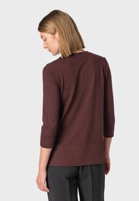 Bordeauxfarbenes Longsleeve mit Rundhalsausschnitt und Dreiviertelärmeln, aus weichem Material gefertigt, mit lockerer Passform und glatter Textur.