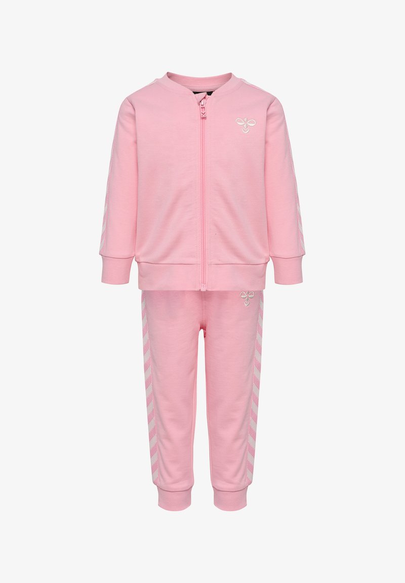 Ensemble sweat-shirt et pantalon rose en matériau doux avec zip, présentant des accents rayés blancs sur les manches et les côtés, ainsi qu'un logo.