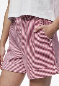 Pantaloni corti a righe rosse e bianche con risvolto e tasche laterali. Realizzati in un tessuto leggero, presentano una vestibilità comoda e un design plissettato.