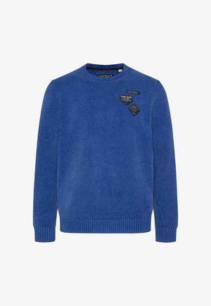 Maglione blu lavorato a maglia con scollo rotondo, polsini e orlo a coste, caratterizzato da tre toppe di tessuto cucite sul petto. Texture morbida.