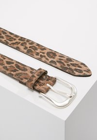 Leopard print faux suede belt with a silver metal buckle, flat design, and a smooth texture, featuring multiple holes for adjustment.