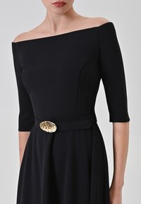 Schulterfreies schwarzes Kleid mit Dreiviertelärmeln, aus glattem Stoff gefertigt, mit einem breiten Gürtel und einer glänzenden goldenen Schnalle.
