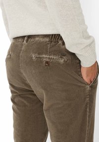 Pantaloni in corduroy verde oliva, con una texture a coste, tasche posteriori con bottoni e una cintura elastica per il massimo comfort.