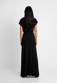 Gonna maxi nera e top a maniche corte blu navy con paillettes. Il tessuto sembra morbido e fluido, progettato per una vestibilità comoda.