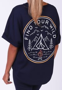 Navyblauwe oversized t-shirt van zachte stof, met een witte en oranje graphic design met een kampeerthema op de achterkant.