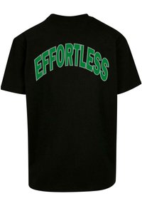 Camiseta de algodón negra con un destacado texto verde en arco "EFFORTLESS" en la parte posterior. Manga corta y corte relajado.
