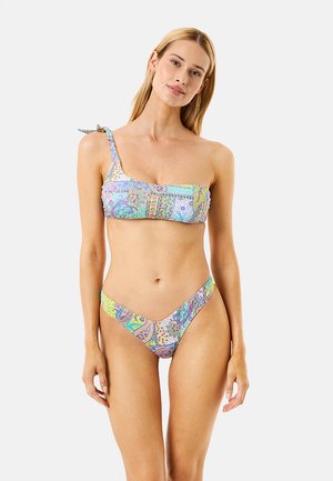 Donna che indossa un bikini con motivo paisley in colori pastello, con top monospalla e slip a vita alta, in piedi contro uno sfondo chiaro e uniforme.