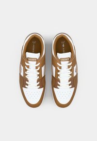 Brown and white sneakers with a textured leather and textile upper, featuring perforations on the toe box and lace-up closure.