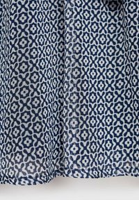 Modra in bela tkanina z ponavljajočim se cvetličnim vzorcem; lahka, polprosojna tekstura; vsebuje zapletene geometrijske vzorce.