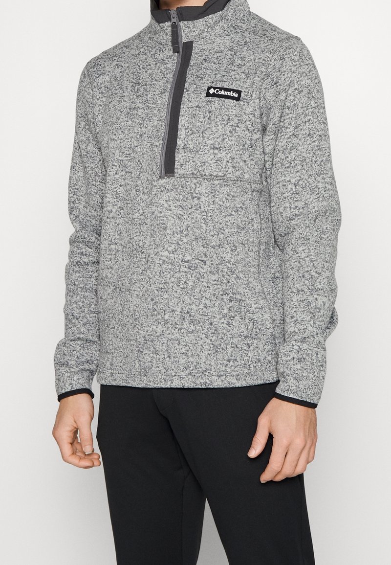 Pullover in fleece grigio a fantasia con mezza zip, colletto alto e tasca sul petto. Presenta finiture nere e un piccolo logo sul davanti.