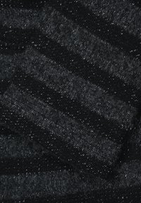 Svart randig stickad tyg med varierade texturer och glänsande silvertrådar som är insprängda, vilket skapar ett subtilt mönster. Mjuk och varm känsla.