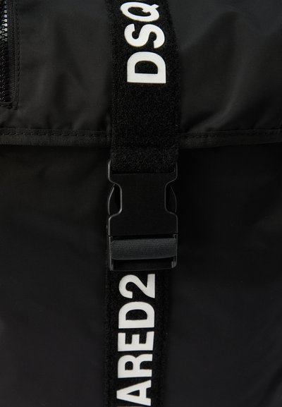 Μαύρο υφασμάτινο λουράκι με λευκή επιγραφή "DSQUARED2" και πλαστική αγκράφα κλεισίματος σε μαύρο υφασμάτινο φόντο.