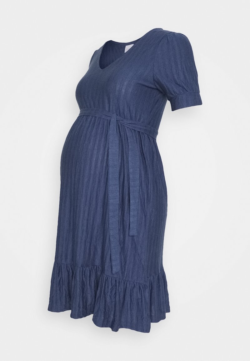 Robe de maternité bleu marine avec des manches courtes bouffantes, décolleté en V et taille à nouer. Présente un ourlet volanté et une texture à côtes verticales.