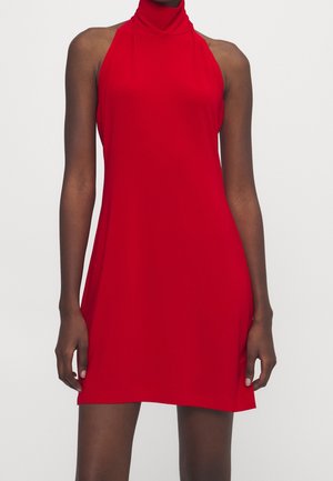 Sleeveless red mini dress with high neckline worn by a person, showing upper torso and legs against plain background.