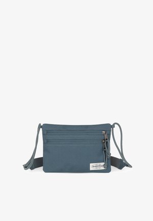 Bolso cruzado de tela azul con múltiples compartimentos con cremallera, correa ajustable y superficie texturizada. Presenta una etiqueta de logo en la parte frontal.