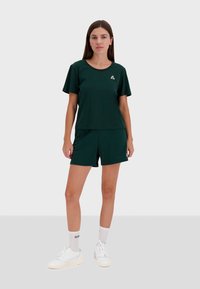 Dark green, short-sleeved t-shirt with a round neckline paired with matching shorts. Features a small logo on the chest. Simple and casual design.