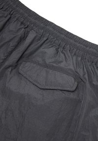 Black crinkled fabric with elastic waistband and a stitched rectangular flap pocket with angled edges on casual shorts.